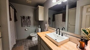 A bathroom with a white sink, a mirror, and a toilet. - FamilyFriendly 2BR,King bed @ Fort Sill & Lawton #1 (Elgin)