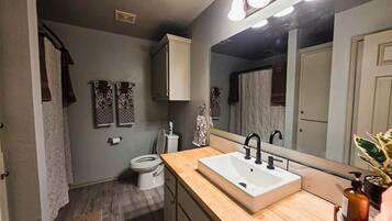 A bathroom with a white sink, a mirror, and a toilet.