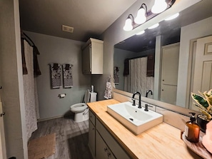 Een badkamer met een wit wastafel, een spiegel en een toilet.