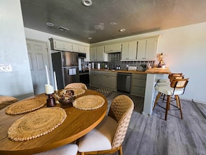 Een moderne keuken met een eethoek, met een houten tafel, geweven placematen en rieten stoelen.