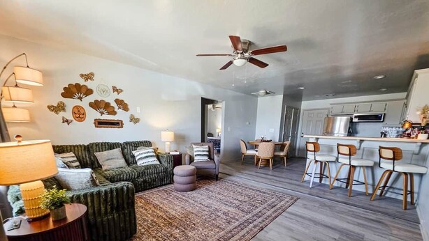 A modern living room with a sofa, ottoman, and a dining area with bar stools. - FamilyFriendly 2BR,King bed @ Fort Sill & Lawton #1 (Elgin)