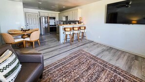 A modern kitchen with a central island, bar stools, and a dining area with a round table and cushioned chairs. - FamilyFriendly 2BR,King bed @ Fort Sill & Lawton #1 (Elgin)