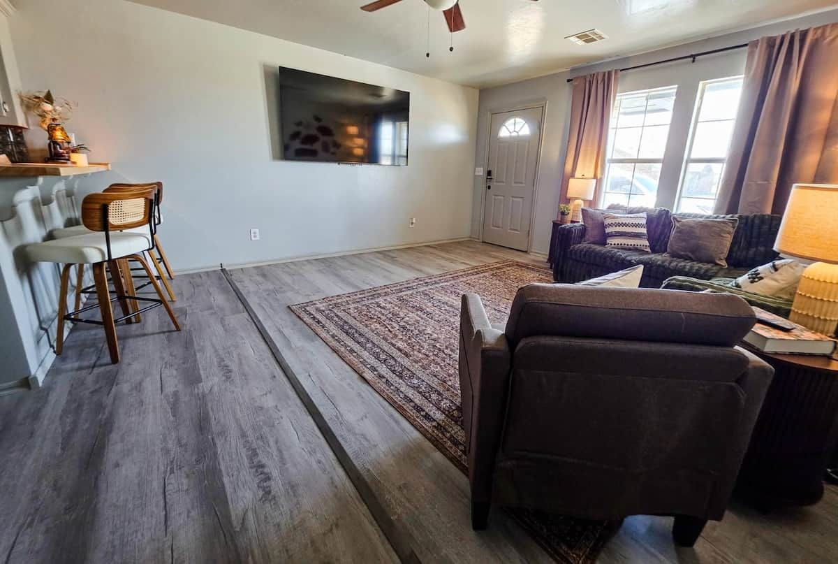 A living room with a sofa, chairs, a TV, and a door.