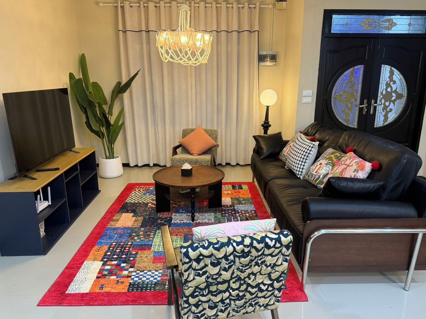 A living room with a sofa, coffee table, TV, and a large plant.