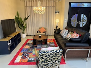 A living room with a sofa, coffee table, TV, and a large plant. - Moon house 5BR Near Walking Street  (Nongprue)
