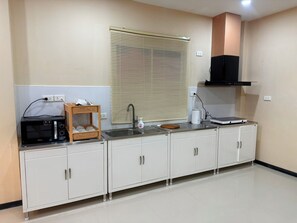 A modern kitchen with a microwave, sink, and cabinets. - Moon house 5BR Near Walking Street  (Nongprue)
