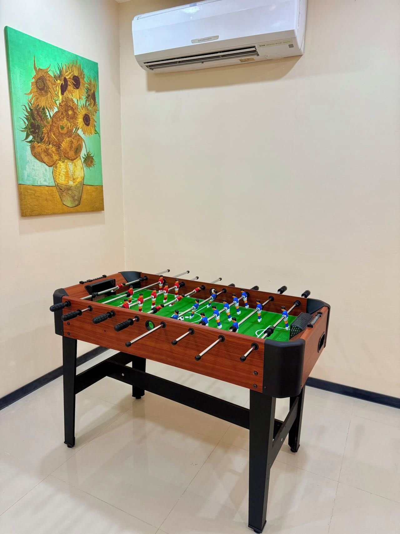 Une pièce avec une table de baby-foot, un tableau accroché au mur et un appareil de climatisation.