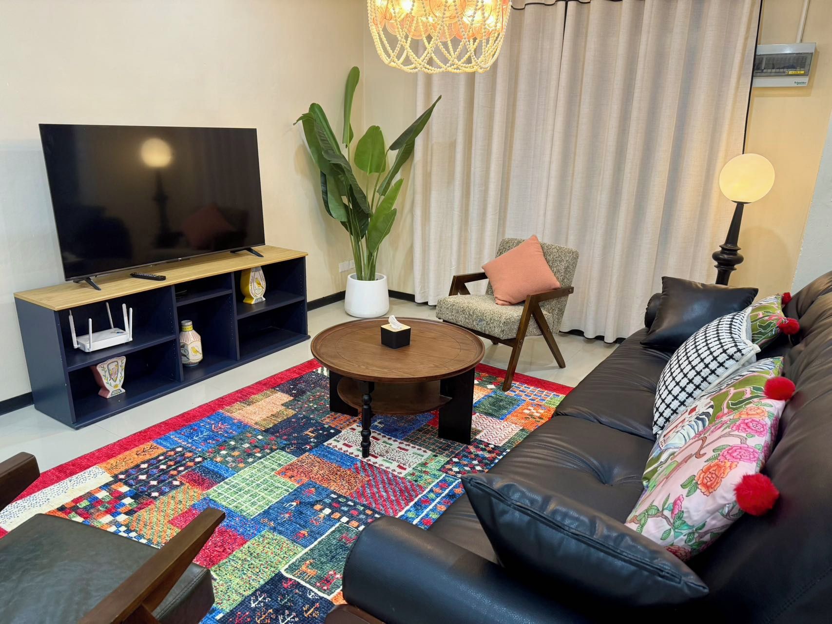 Ein Wohnzimmer mit Fernseher, Couch, Couchtisch und einem farbenfrohen Teppich.