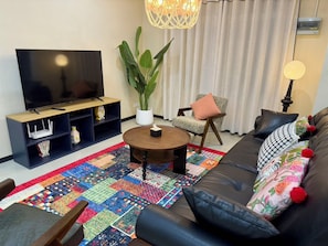 A living room with a television, a coffee table, a sofa, and a colorful rug. - Moon house 5BR Near Walking Street  (Nongprue)