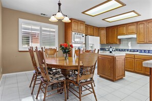 A kitchen with wooden cabinets, a dining table with chairs, a microwave, and a refrigerator. - 3 bedroom beach view home in Morro Bay! Room for the family- medium term rental (Morro Bay)