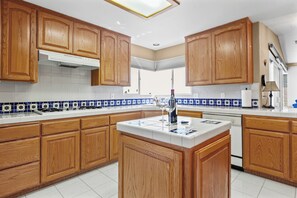 A kitchen with wooden cabinets, a central island, and blue and white patterned backsplash. - 3 bedroom beach view home in Morro Bay! Room for the family- medium term rental (Morro Bay)
