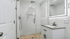 A modern bathroom with a glass shower enclosure, a vanity with a sink, and a large mirror. - On the Pier Cottage with Direct Beach Access (Santa Monica)