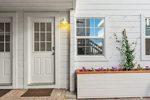 A white door with a glass panel, a light fixture above it, and a window with a view of a building.