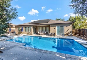 A residential property with a swimming pool, patio furniture, and a covered outdoor seating area. - Comfortable & Spacious Riverlakes 4BR Home perfect for traveling professionals (Bakersfield)