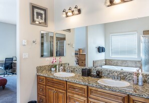 A bathroom with two sinks, a large mirror, and a shower.