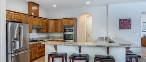 Una cocina moderna con electrodomésticos de acero inoxidable, armarios de madera y encimera de granito.