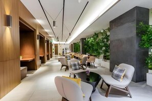 A modern hotel lobby with a long corridor, seating areas, and a large planter with greenery. - Home Inn Plus Shanghai Pudong Jinqiao (Shanghai)
