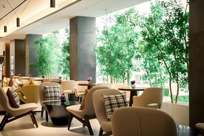 A modern lounge area with sofas and tables, large windows with greenery outside, and a minimalist design. - Home Inn Plus Shanghai Pudong Jinqiao (Shanghai)