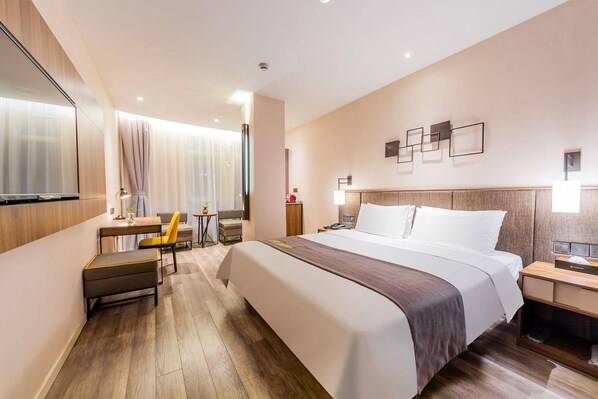 Une chambre d’hôtel avec un grand lit, un bureau avec une chaise, une petite table et un téléviseur.