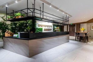 A modern reception area with a counter, plants, and a dining area with chairs and a table. - Home Inn Plus Shanghai Pudong Jinqiao (Shanghai)