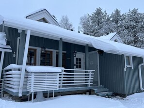 A snow-covered building with a porch and a stack of white chairs. - Renovated 2 BD+ loft by the lake, free wifi, sauna (Kuusamo)