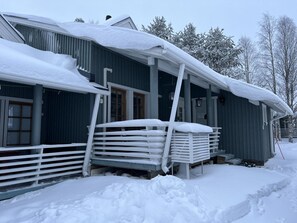 A snow-covered building with a porch and a stack of white plastic chairs. - Renovated 2 BD+ loft by the lake, free wifi, sauna (Kuusamo)