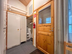 A hallway with a white door, a wooden door with a window, and a fire extinguisher on the wall. - Renovated 2 BD+ loft by the lake, free wifi, sauna (Kuusamo)