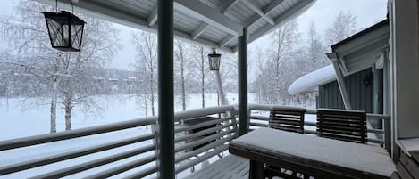 Une terrasse extérieure couverte, dotée d’une table et de chaises, de rampes et de lanternes suspendues.