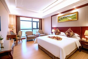 Een hotelkamer met een groot bed, een bureau, een stoel en een raam met uitzicht.