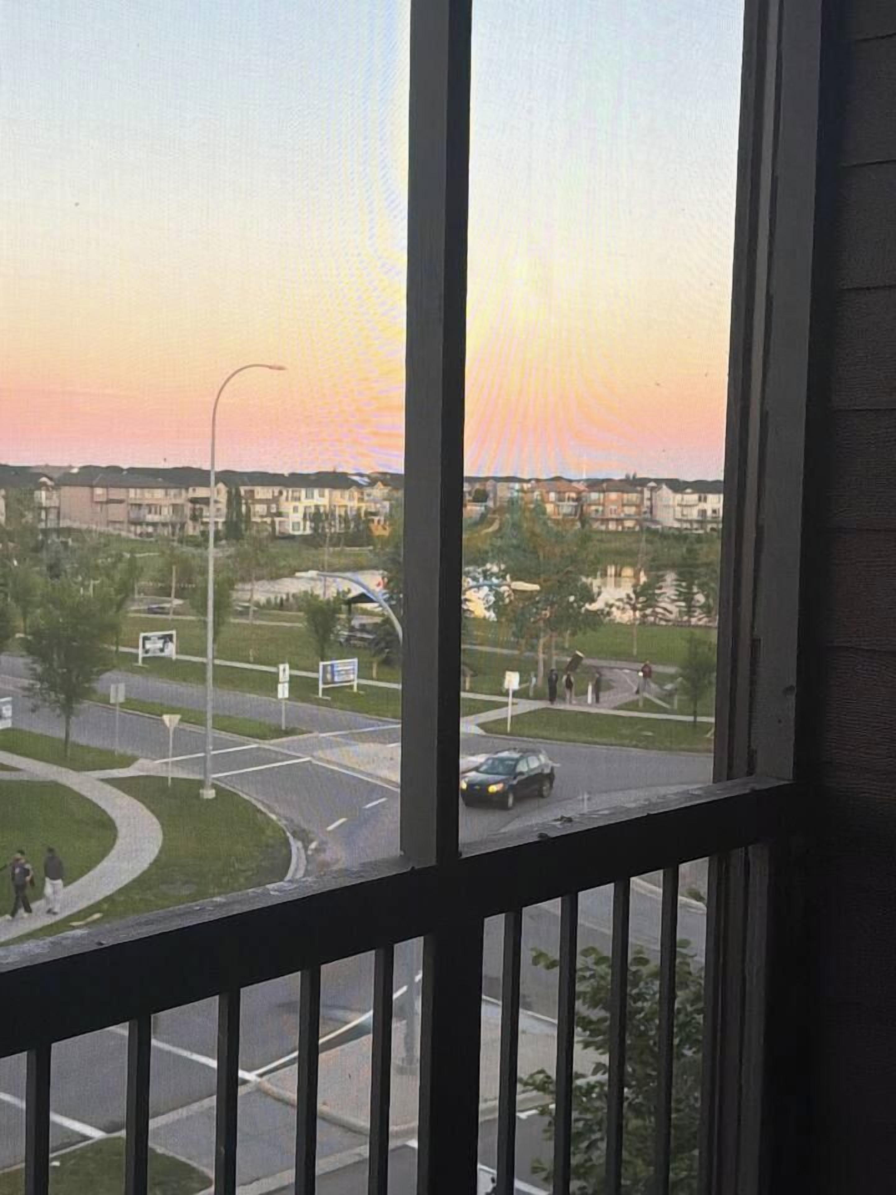 A view from a window overlooking a road with a sunset in the background.