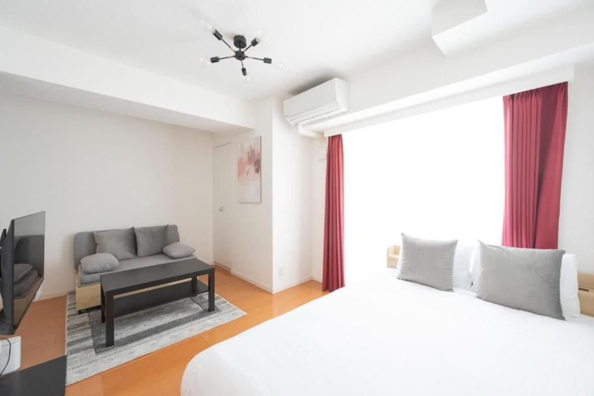 Una camera d'albergo moderna con un letto, una poltrona, una TV e un condizionatore.