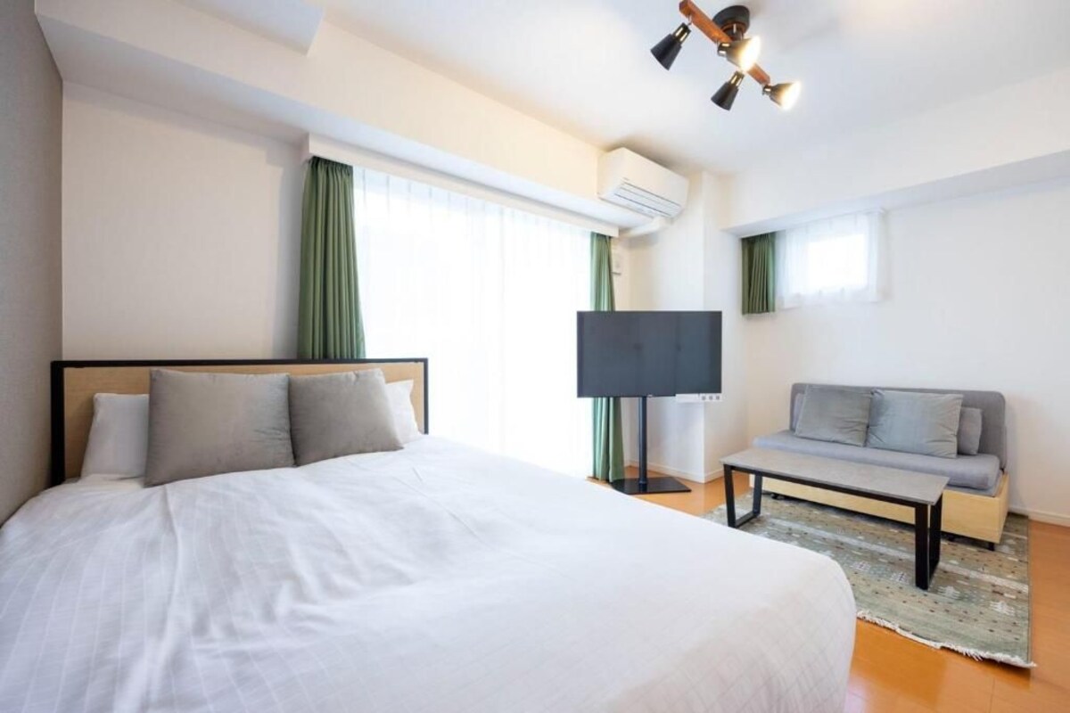 Una camera d'albergo con un letto grande, un divano, una TV e una ventola a soffitto.