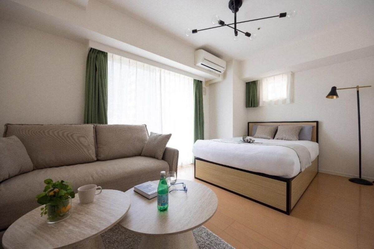Una camera d'albergo moderna con una divisa, un tavolino rotondo, un letto e una lampada da terra.