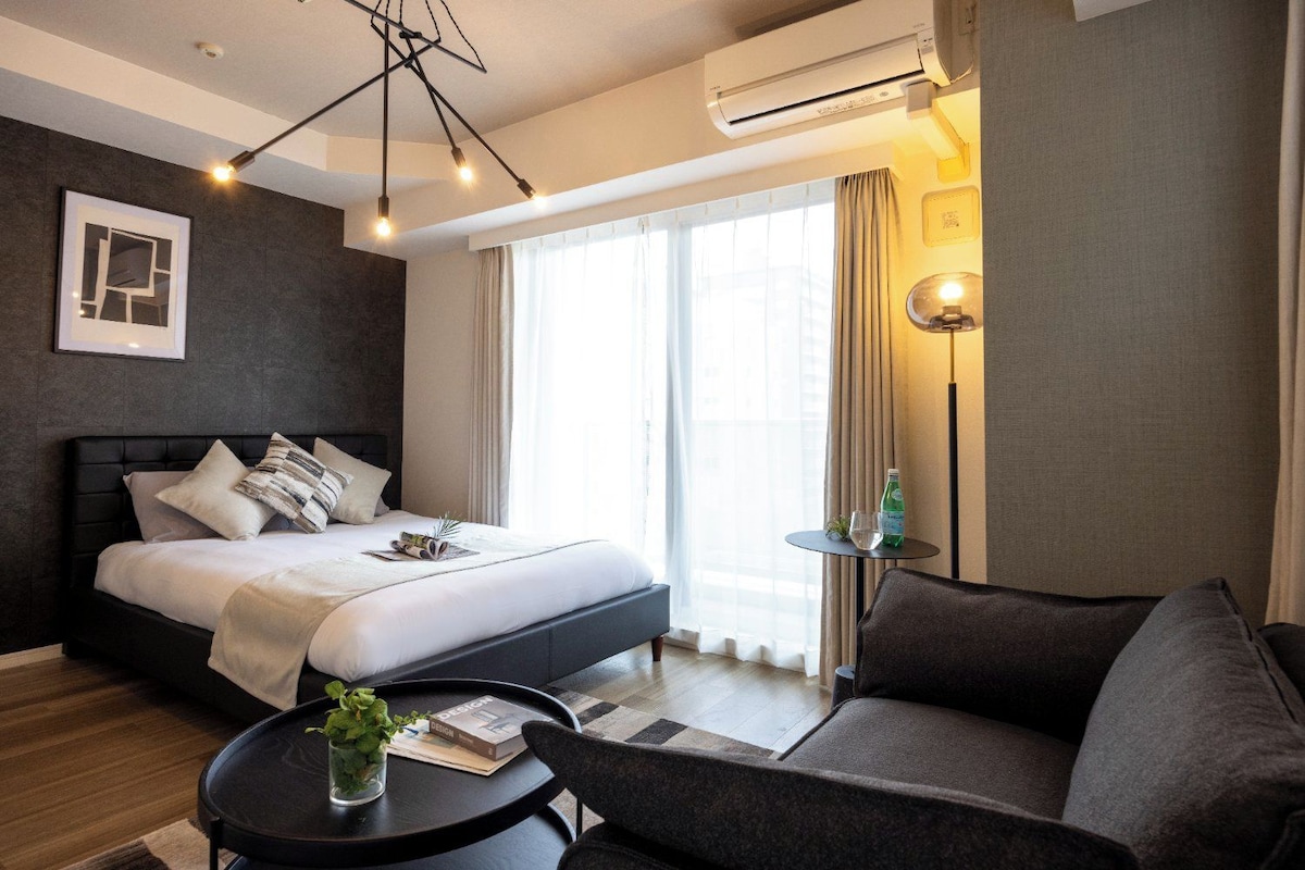 Una camera d'albergo moderna con un letto, un divano, un tavolino e una lampada da terra.