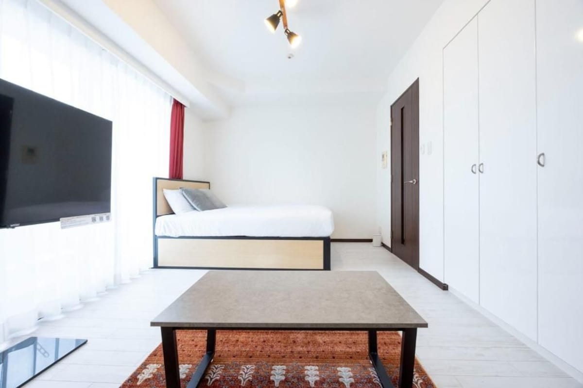Una camera da letto moderna con un letto, una TV a schermo piatto, un tavolo e un armadio.