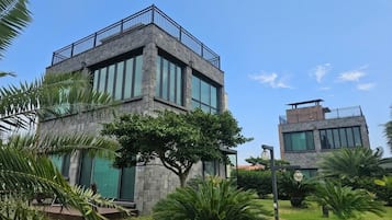 A modern two-story building with a stone facade, large windows, and a balcony.