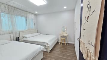 Habitación de hotel con dos camas, un escritorio, un espejo y una pared decorada con un tapiz.