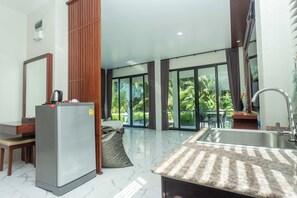 Una cocina moderna con refrigerador, lavamanos y comedor con mesa y sillas.