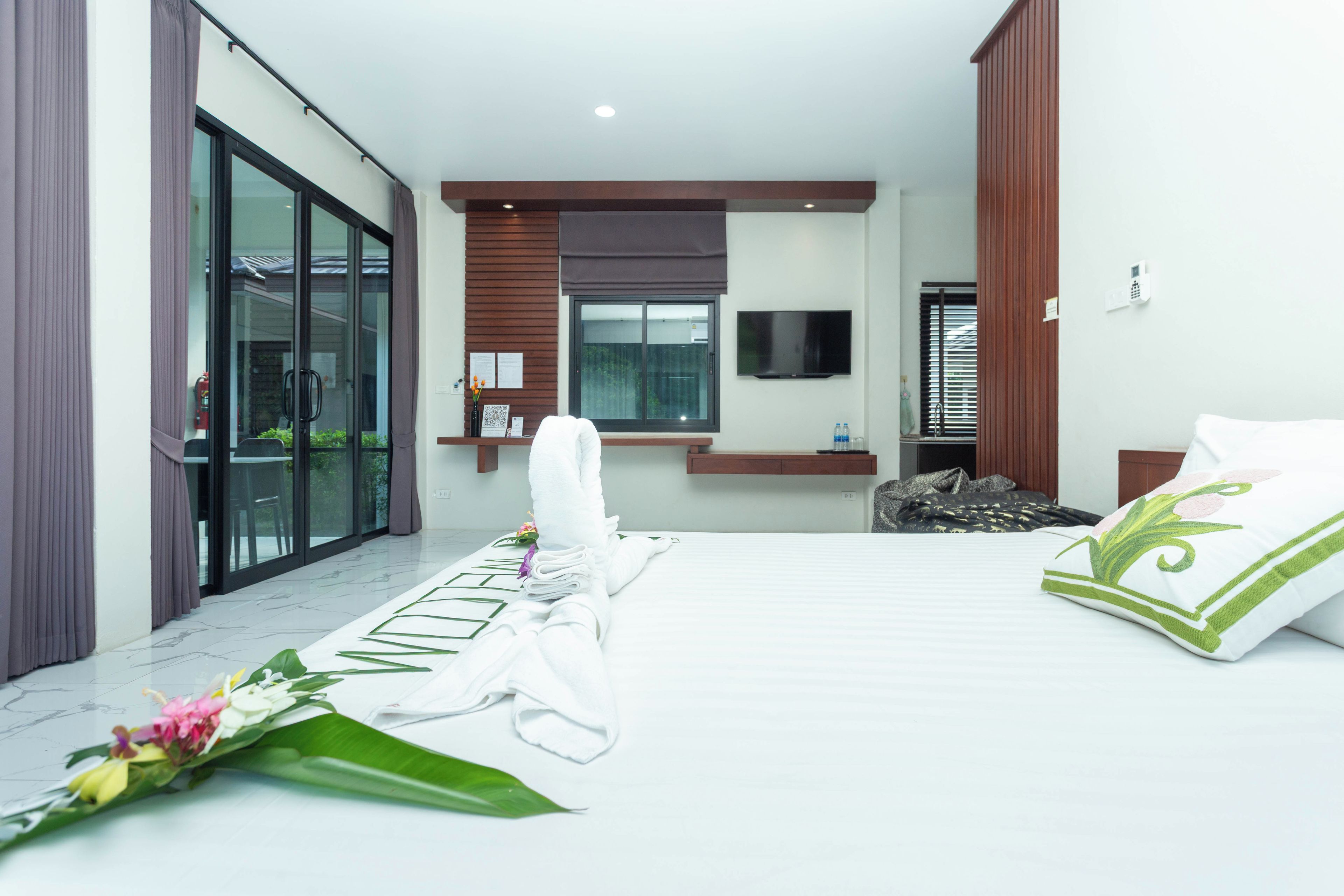 A hotel room with a bed, a TV, a window, and a bathroom.