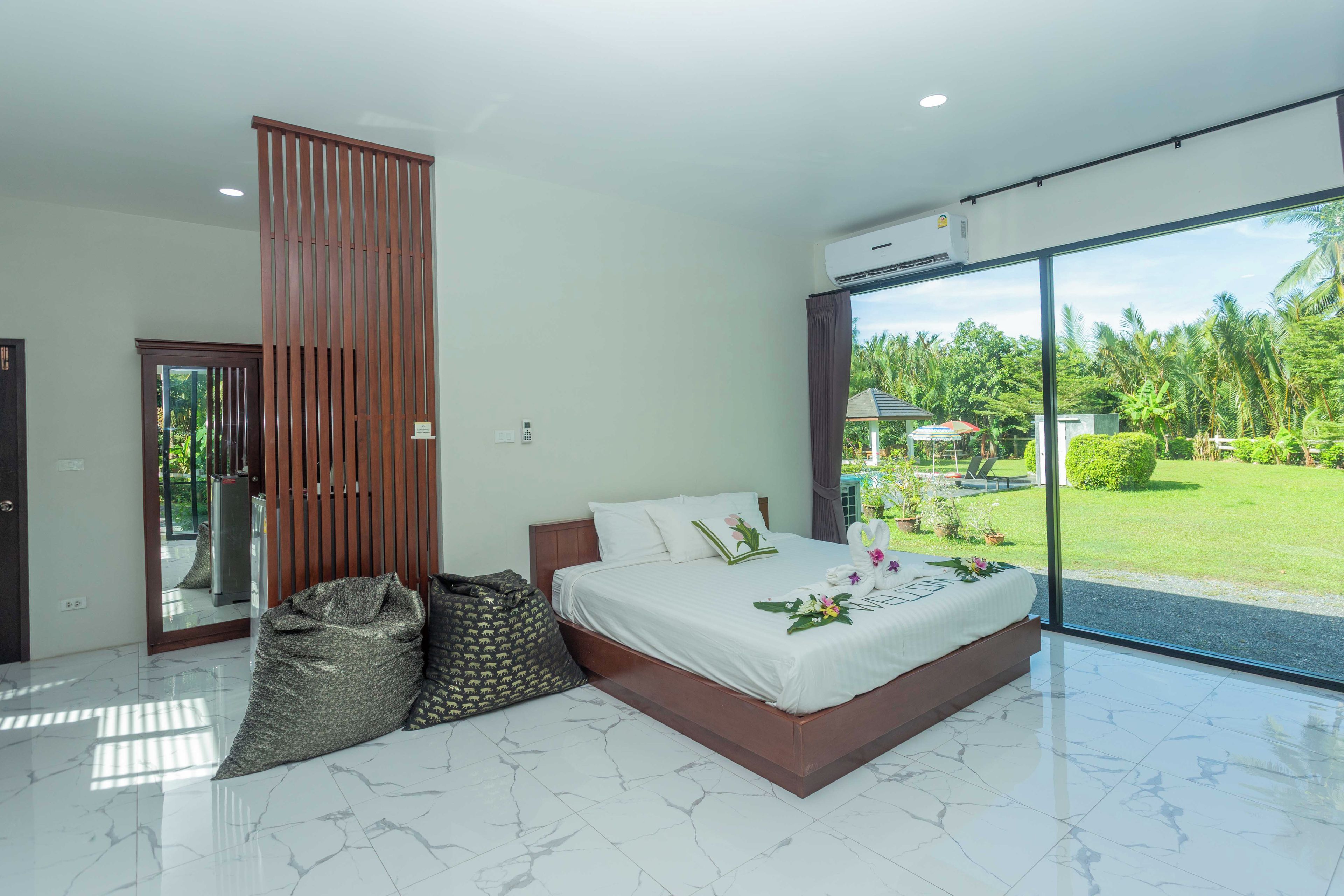 Un dormitorio moderno con una cama grande, una puerta corredera y vistas a un jardín exuberante.