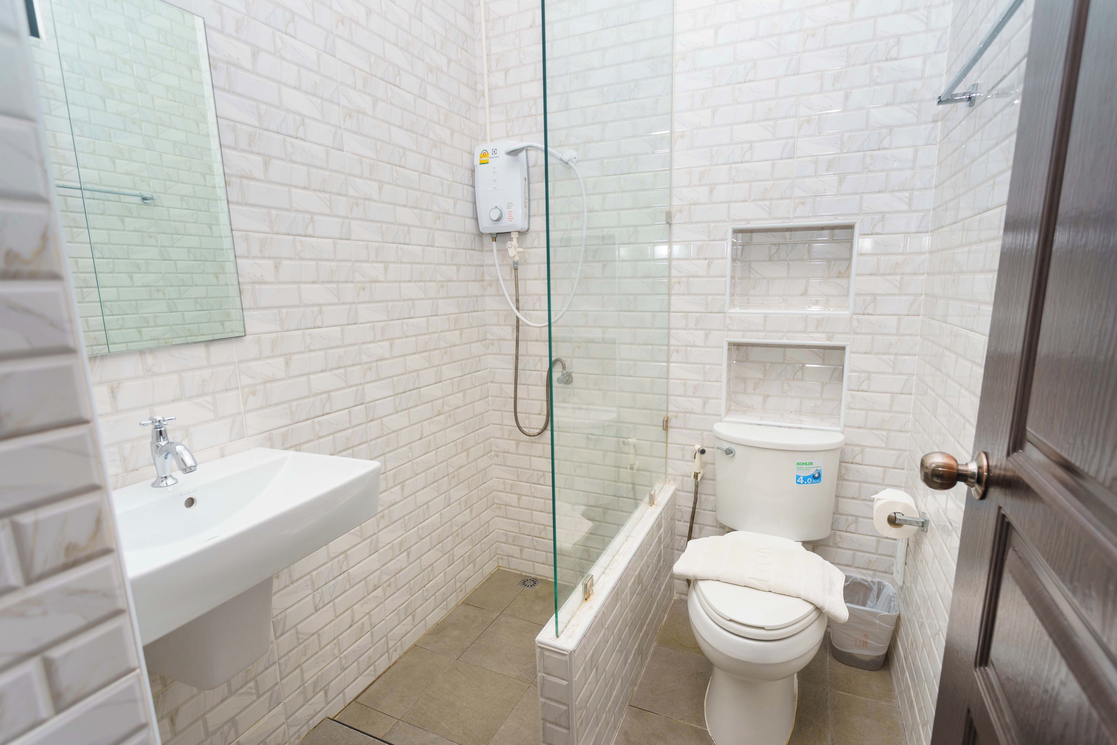 Ein Badezimmer mit einer Duschkabine, einem weißen Waschbecken und einer Toilette.