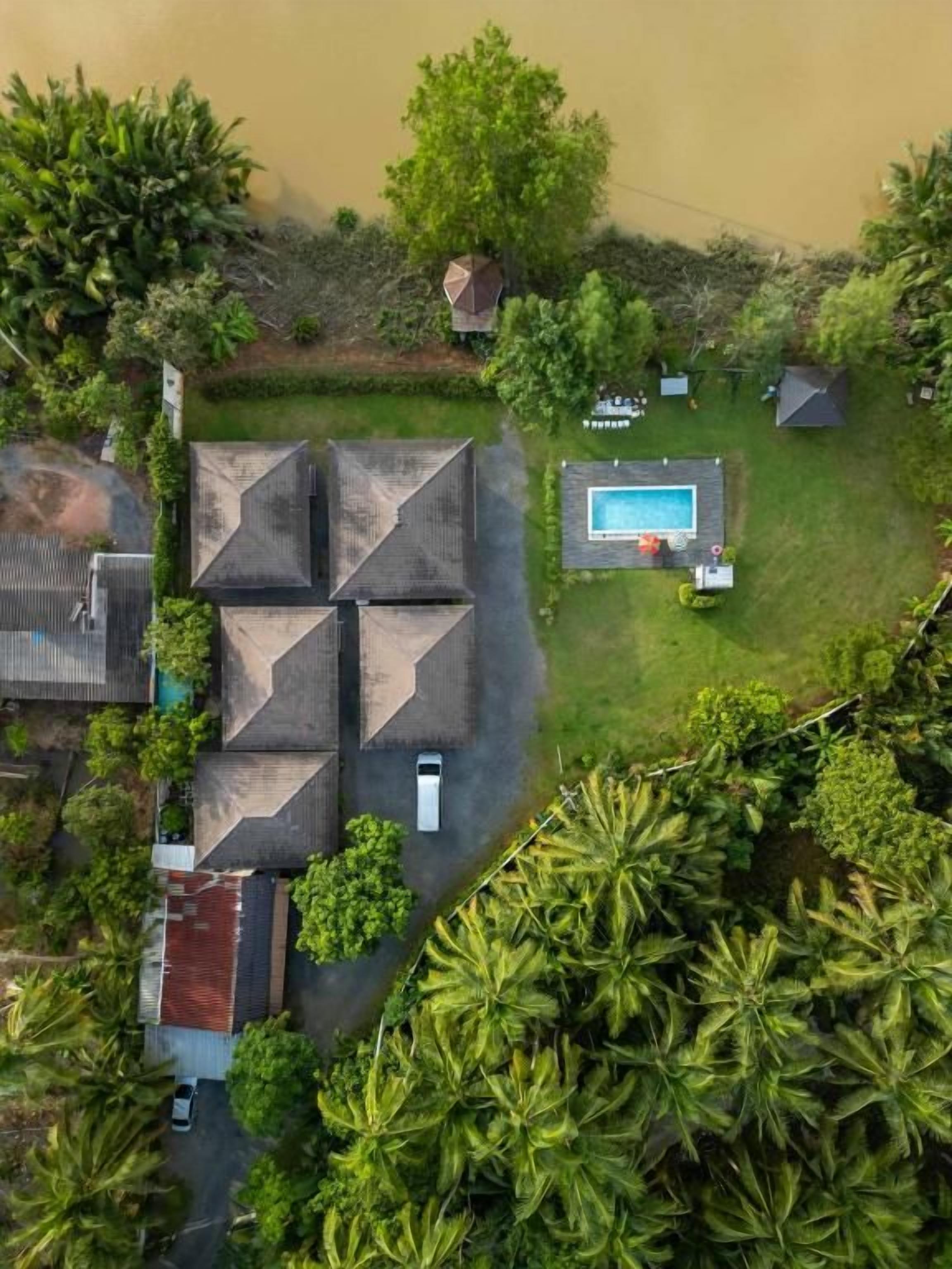An aerial view of a residential area with a swimming pool, multiple houses, and lush greenery.