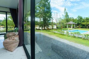 A room with a view of a swimming pool, a gazebo, and a garden.