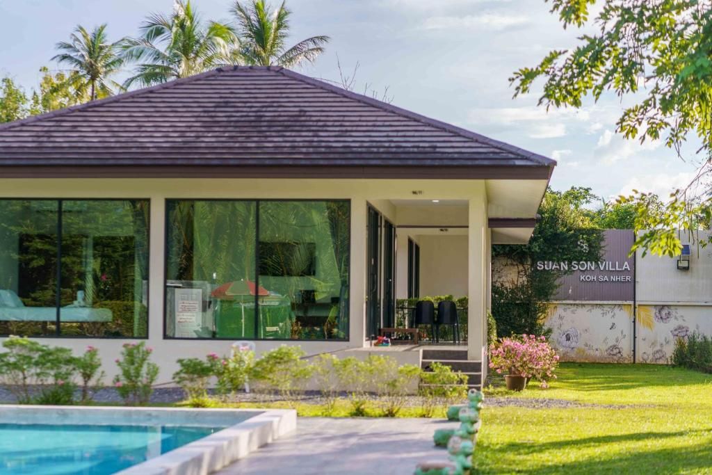 Una villa moderna con piscina, amplios ventanales y un jardín cuidado.