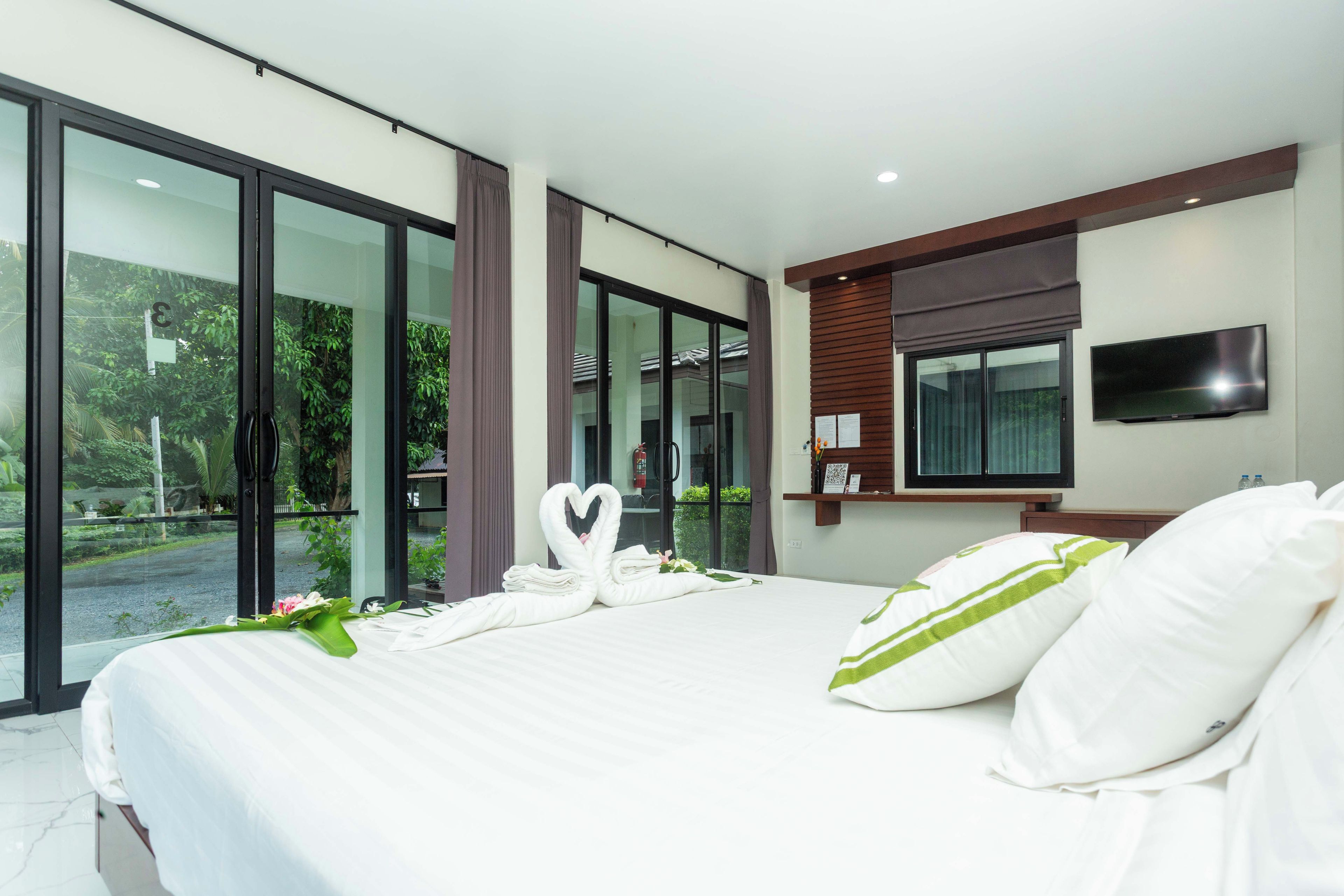 Habitación de hotel moderna con una cama grande, un televisor de pantalla plana y vistas a zonas verdes.