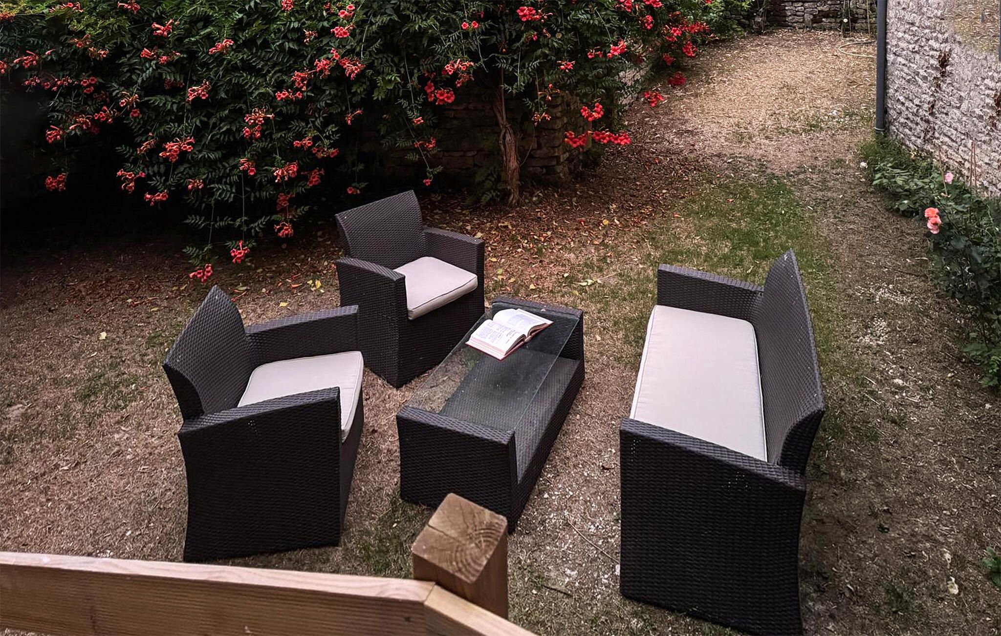 Eine Terrasse mit Gartenmöbeln, darunter eine Couch und Stühle, sowie ein kleiner Holztisch.