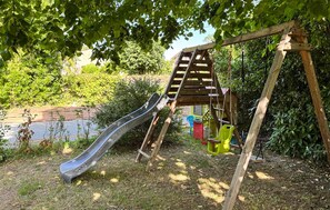 A playground with a slide and swings, surrounded by greenery and a body of water. - 5 bedroom lovely home in Sainte-Néomaye (Sainte-Néomaye)