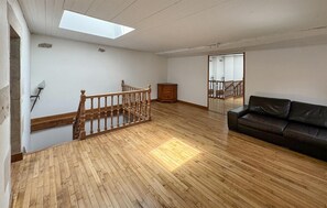 A spacious room with a wooden floor, a brown leather sofa, a wooden staircase, and a skylight. - 5 bedroom lovely home in Sainte-Néomaye (Sainte-Néomaye)