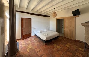Ein Schlafzimmer mit einem Bett, einem Holzschrank, einem an der Wand befestigten Fernseher und einem Fliesenboden.