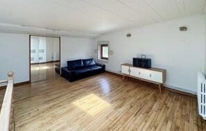 A spacious room with a wooden floor, a black leather sofa, a white cabinet, and a small window. - 5 bedroom lovely home in Sainte-Néomaye (Sainte-Néomaye)